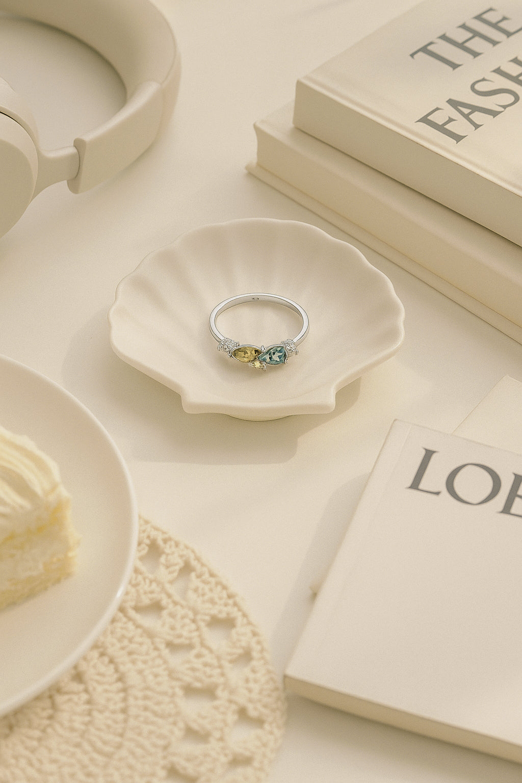 Elegant sterling silver ring with yellow and green gemstones displayed on a shell dish – light luxury jewellery photography